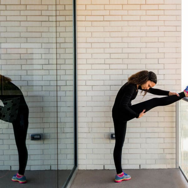 Woman in workout clothes stretching on a balcony