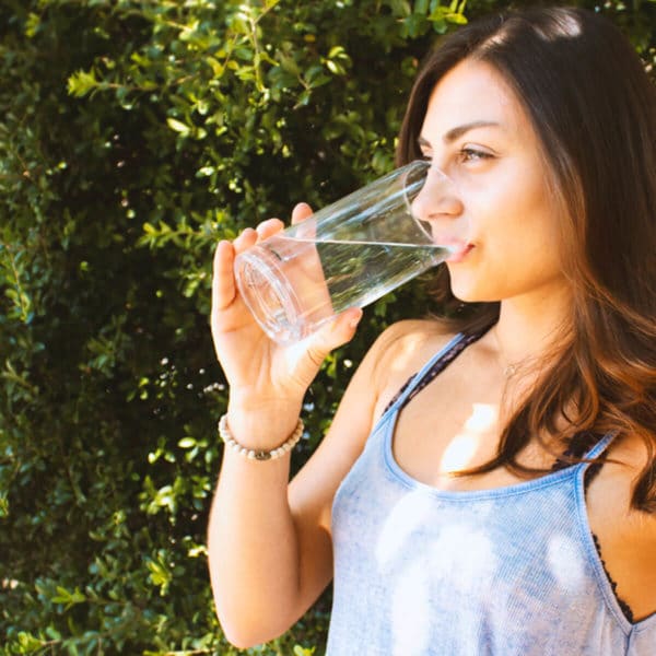 woman with dark hair drinking a glass of water