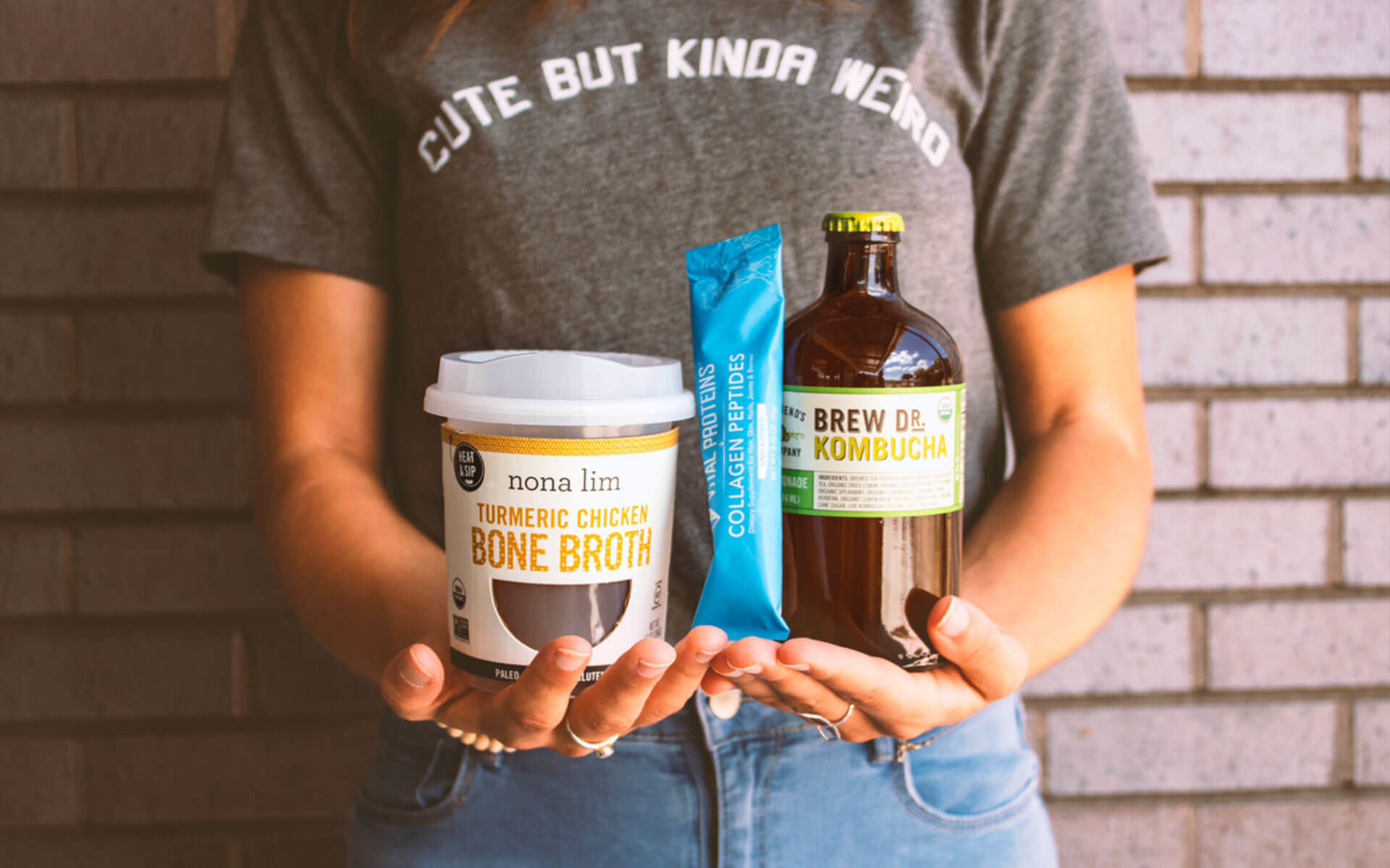person holding containers with bone broth, collagen peptides and kombucha