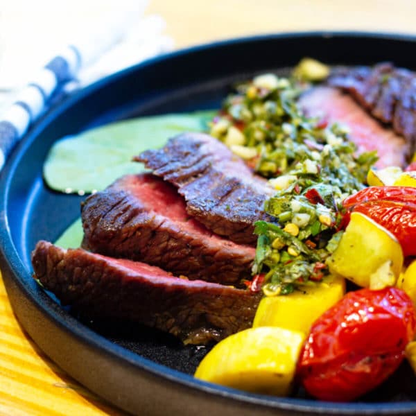 beef and veggies on a black plate