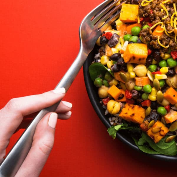 closeup of someone eating a bowl of beef and veggies