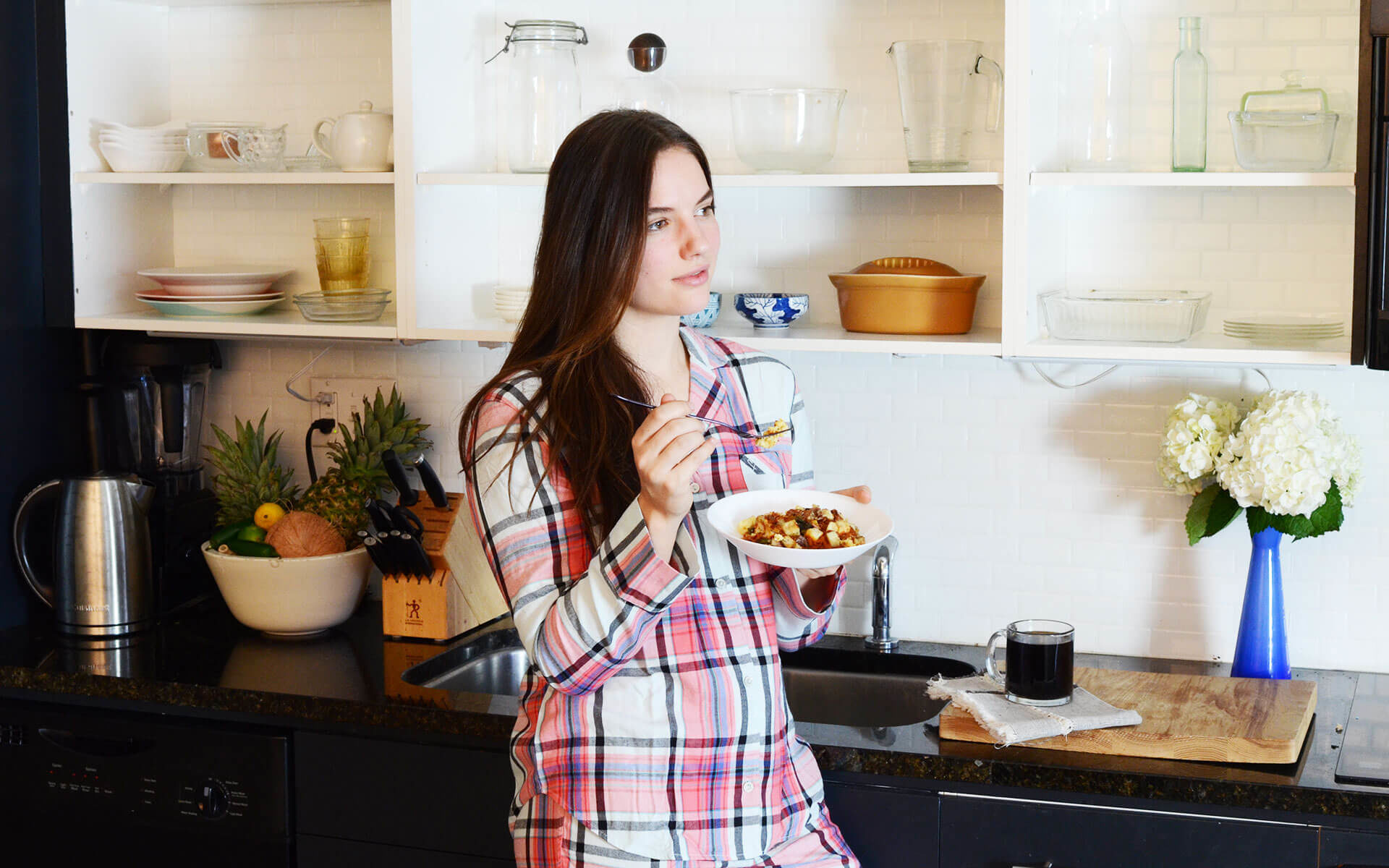 woman in pajamas eating a breakfast bowl