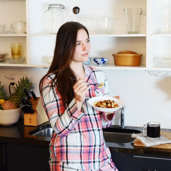 woman in pajamas eating a breakfast bowl