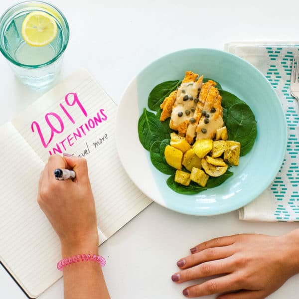 chicken and squash on a plate next to notebook of resolutions