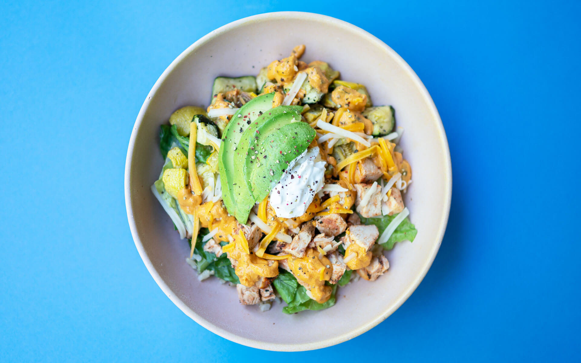 taco bowl with chicken, veggies, avocado and cheese