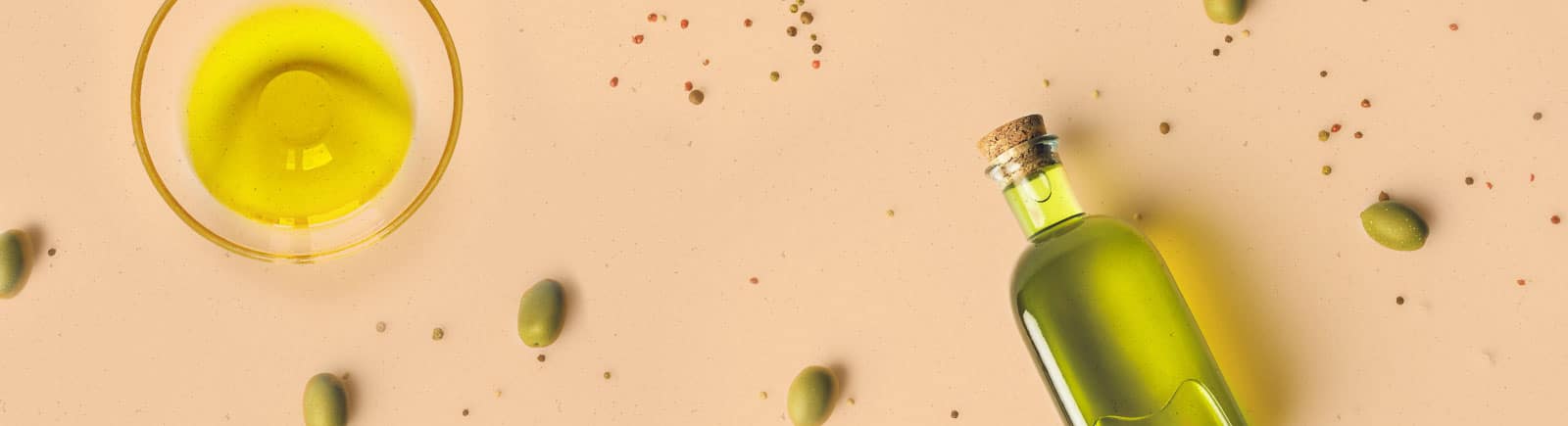 header image of a bottle and bowl of olive oil, with olives scattered throughout