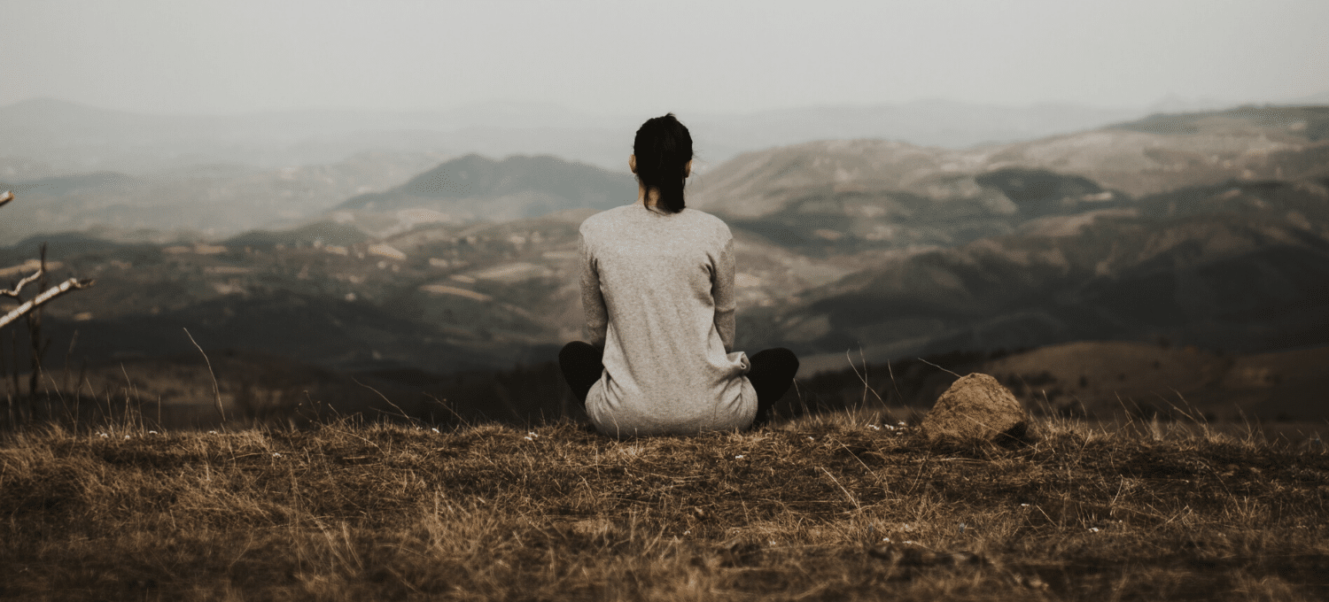 woman meditating in front of mountain landscape