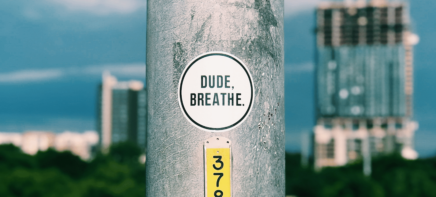 sticker on a utility pole that reads 'Dude, Breathe'
