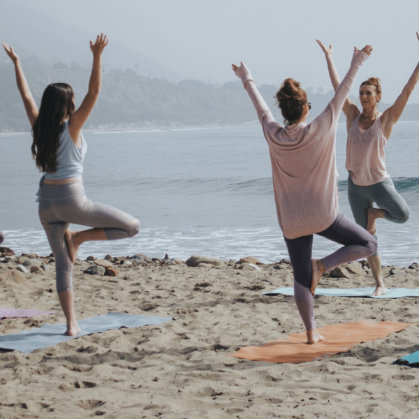 people doing yoga on the beach