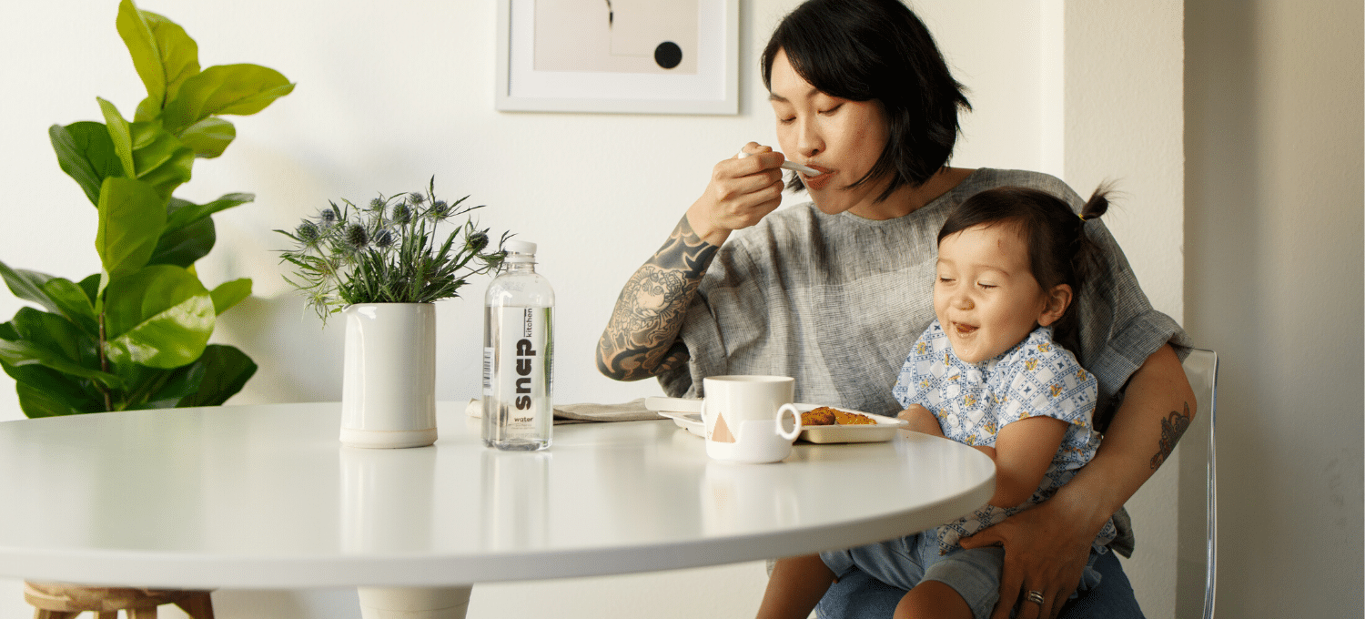 Mom and young child eating at kitchen table