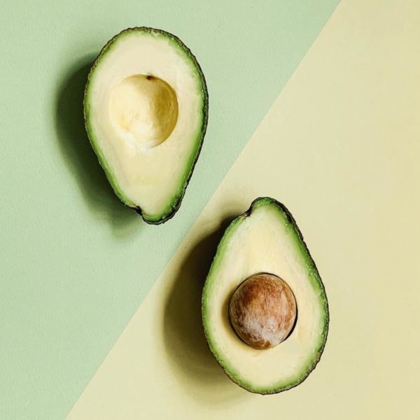 Two halves of an avocado on a yellow and green background