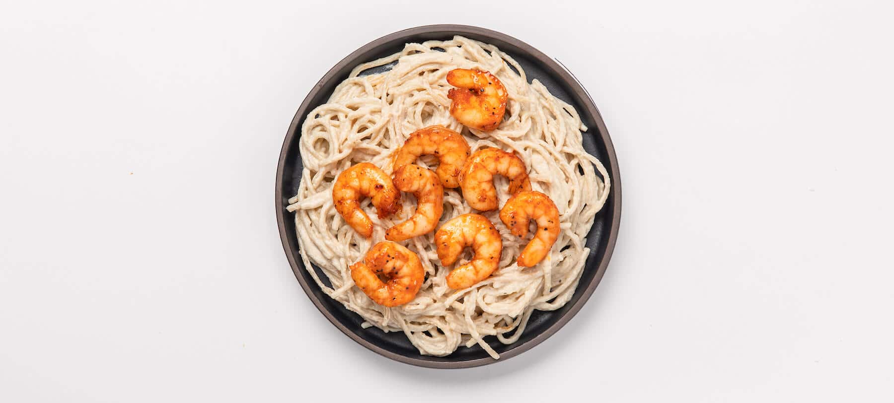 Shrimp alfredo in a bowl on a white background