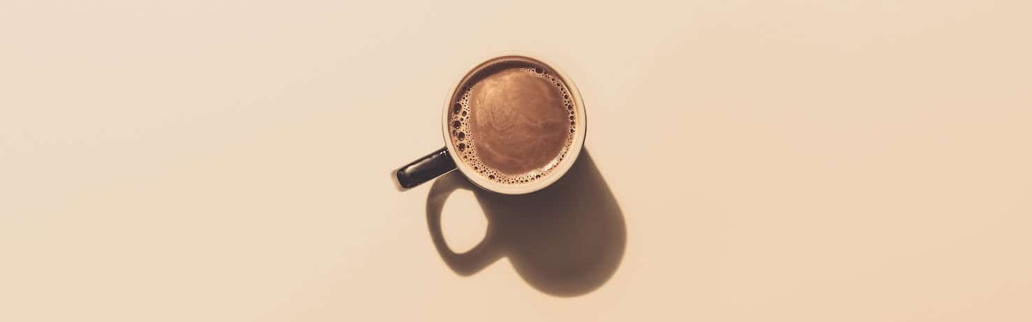 Mug of coffee on a tan background