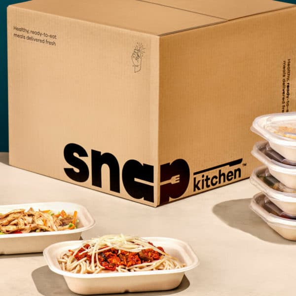 Cardboard Snap Kitchen box with a stack of packaged meals next to it