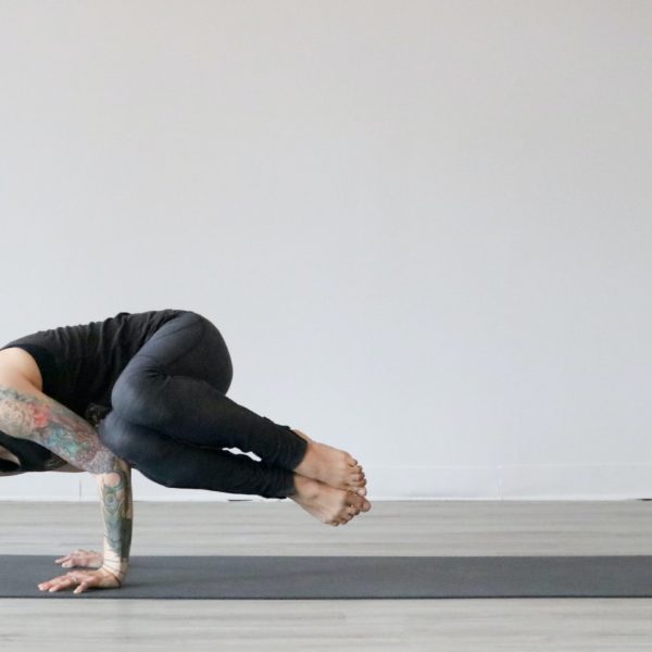 Woman with dark hair and tattoos doing yoga