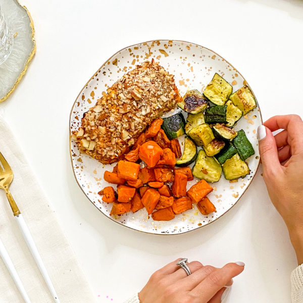 Almond crusted salmon with zucchini and sweet potatoes on a plate with gold accents