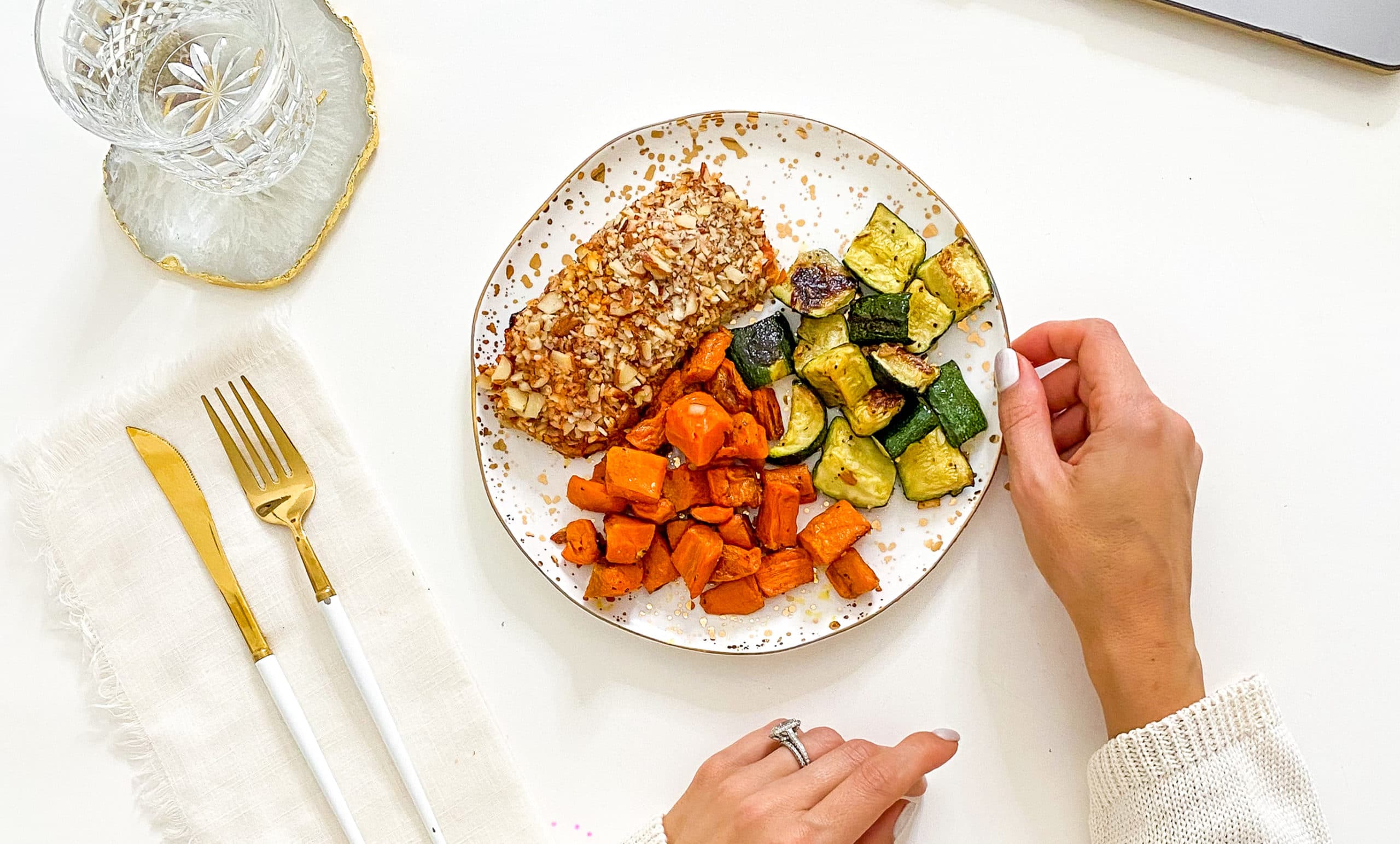Almond crusted salmon with zucchini and sweet potatoes on a plate with gold accents