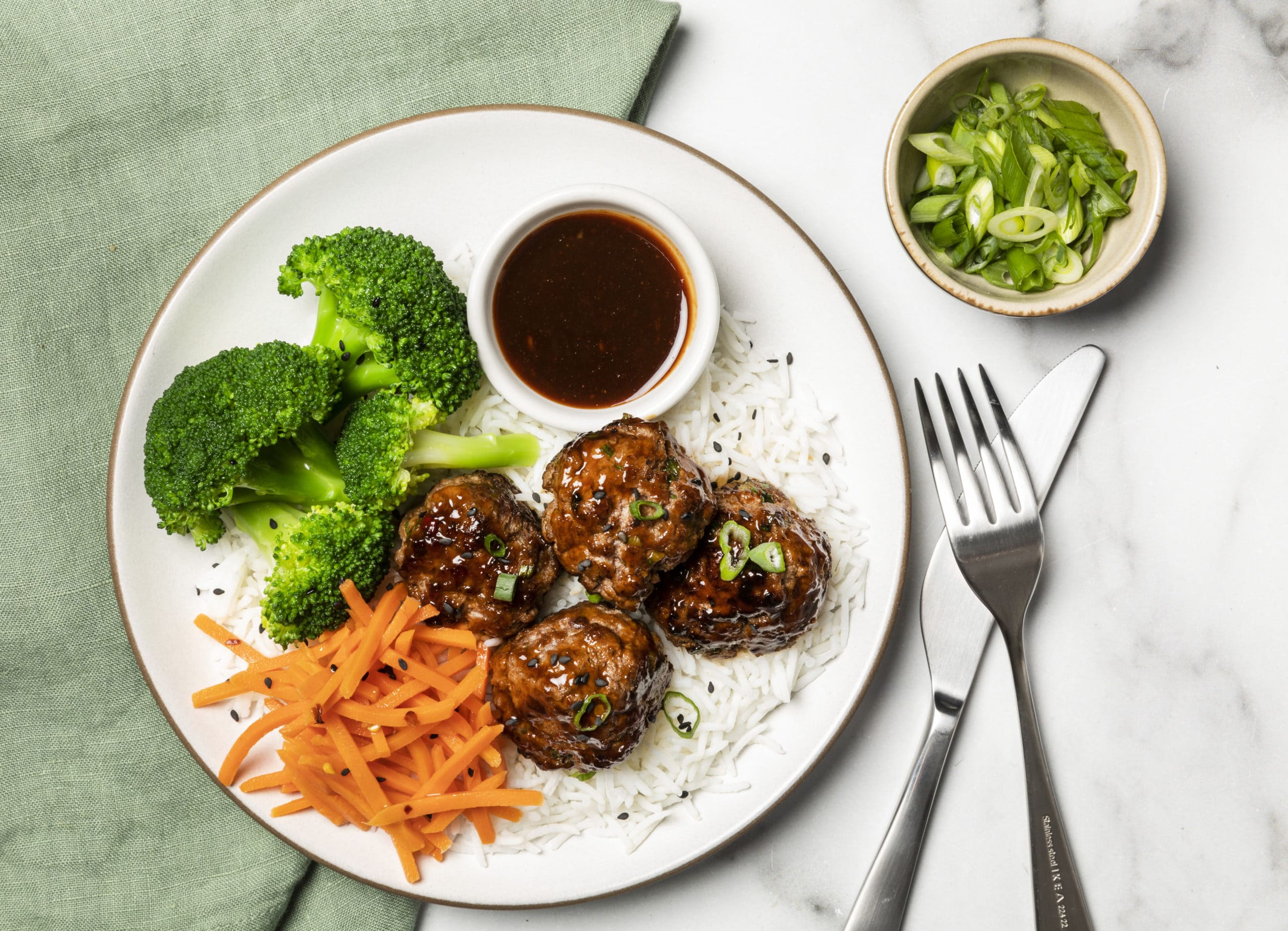 A plate of Korean meatballs with broccoli and carrots