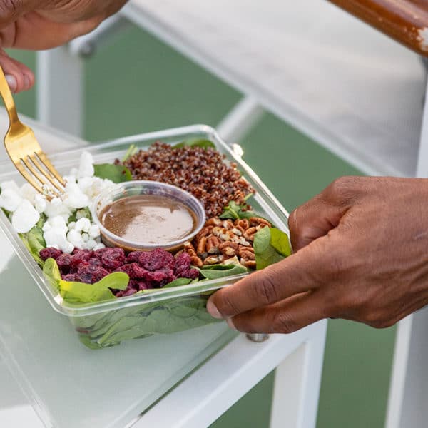 Close up of someone eating a salad with feta, dried cranberries and walnuts on it