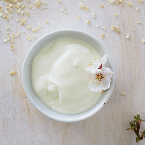Small bowl of aioli with flower garnish on a white marble countertop