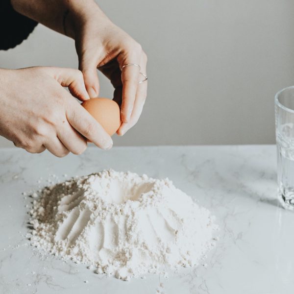 Someone cracking an egg into a pile of almond flour
