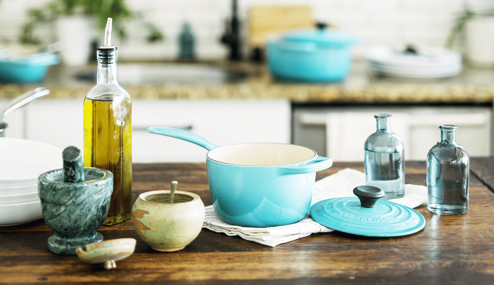 Kitchen counter with a mortar & pestle, blue ceramic pots and pans and various cooking oils