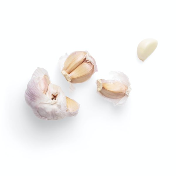 Piece of garlic broken into single cloves on a white background