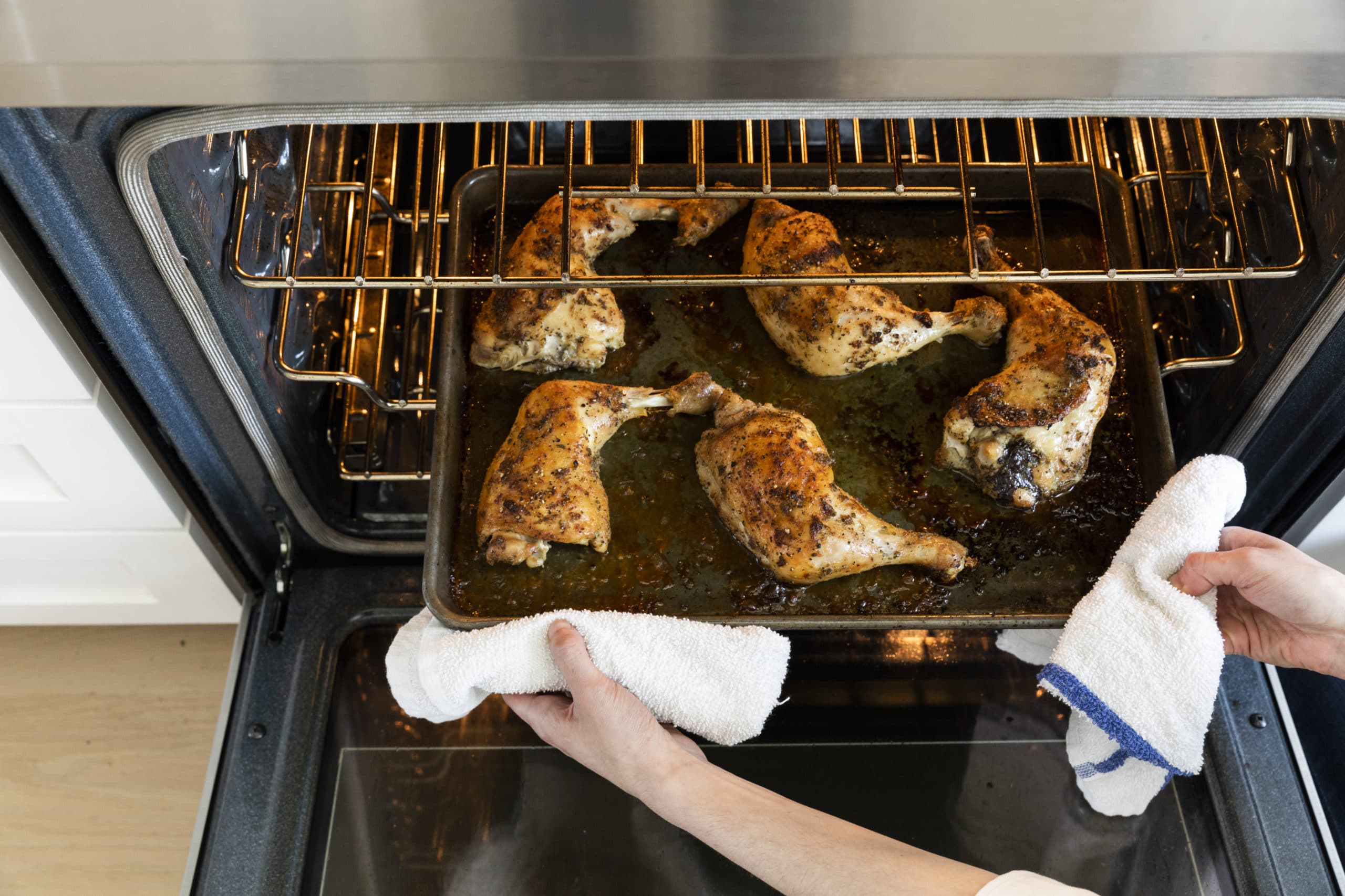 Roasted chicken thighs on a pan being placed into the oven