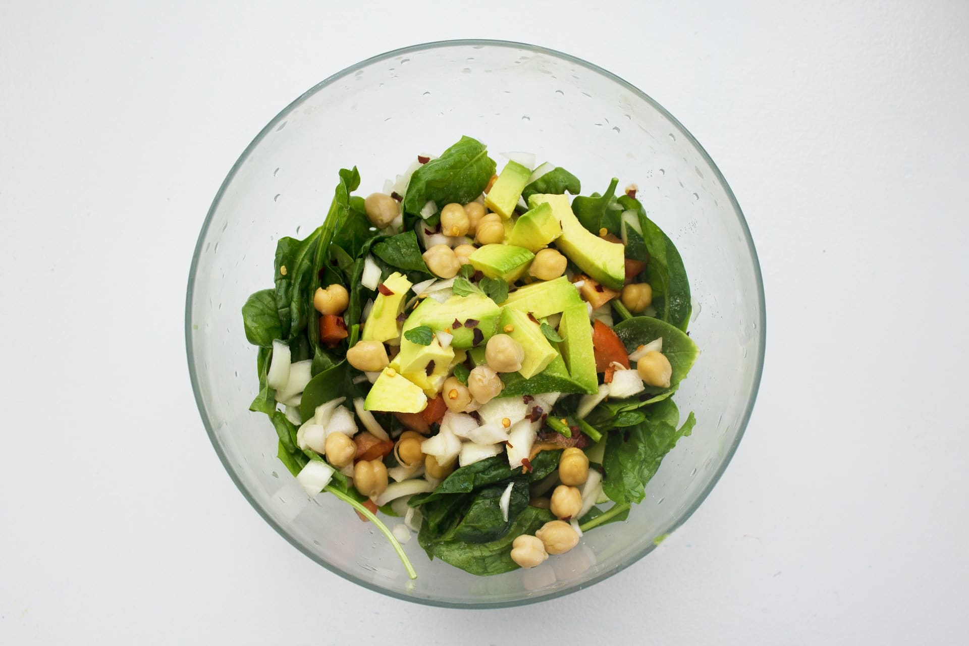 Mixed green salad with chickpeas, avocado, onions, and more