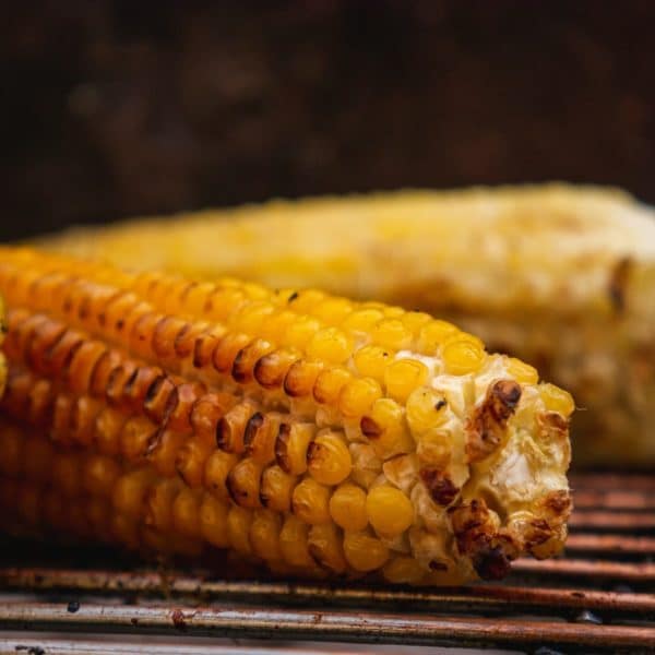 corn on the cob being roasted over a grill