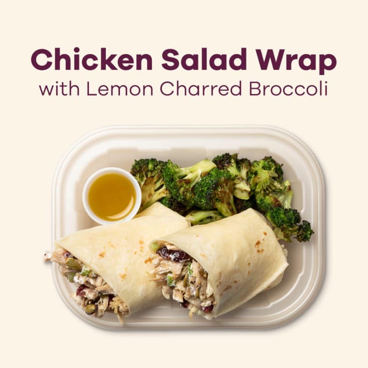 a chicken salad wrap on a white plate with broccoli 