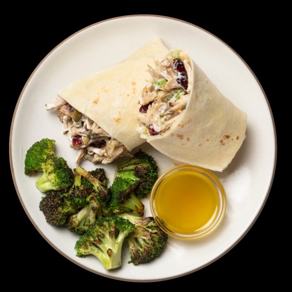 a chicken salad wrap on a white plate with broccoli