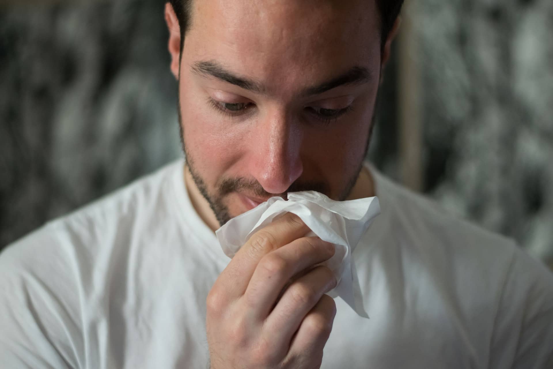 man wiping nose with a tissue